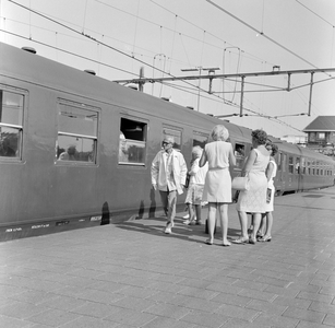 881770 Afbeelding van reizigers bij de Zonexpres langs het perron van het N.S.-station Amsterdam C.S.